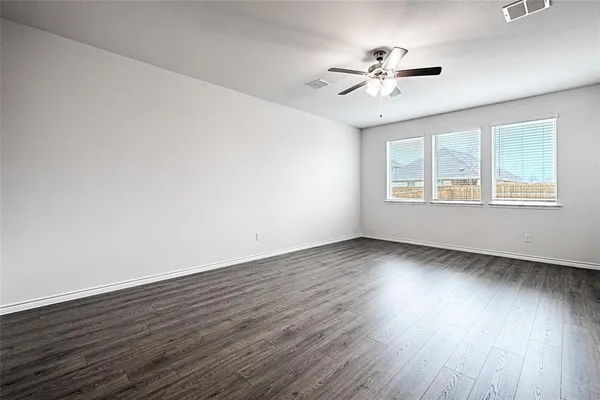 an empty room with wooden floor window and ceiling fan