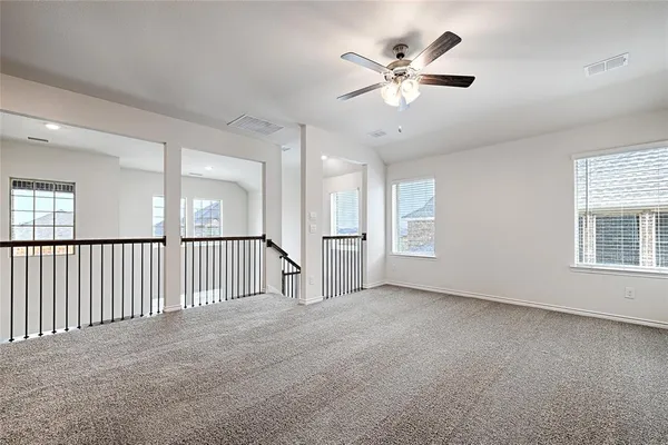 an empty room with windows and ceiling fan
