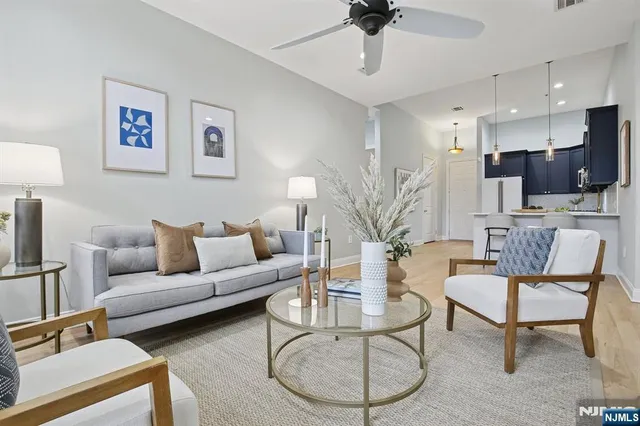 a living room with furniture a flat screen tv and a ceiling fan