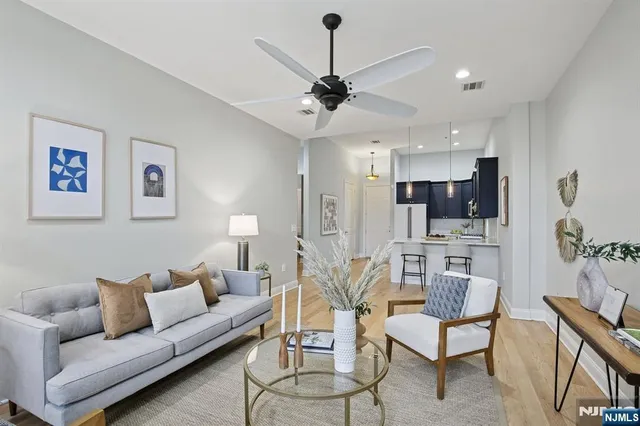 a living room with furniture kitchen view and a chandelier