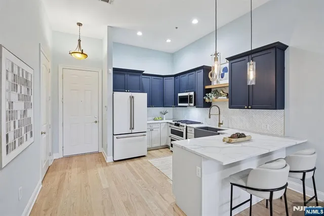 a kitchen with granite countertop a refrigerator a stove a sink dishwasher a dining table and chairs with wooden floor