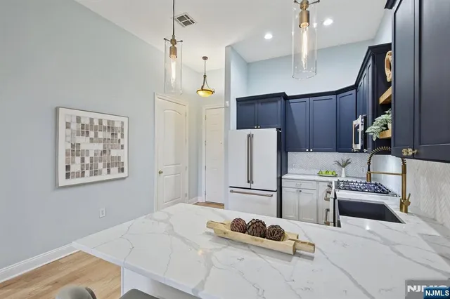 a kitchen with stainless steel appliances kitchen island granite countertop a refrigerator stove and sink