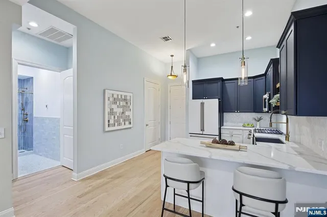 a kitchen with stainless steel appliances kitchen island granite countertop a sink and refrigerator