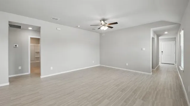 an empty room with wooden floor ceiling fan and window