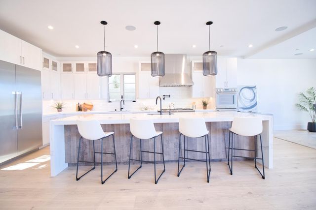 a kitchen with stainless steel appliances kitchen island granite countertop a table chairs and a sink