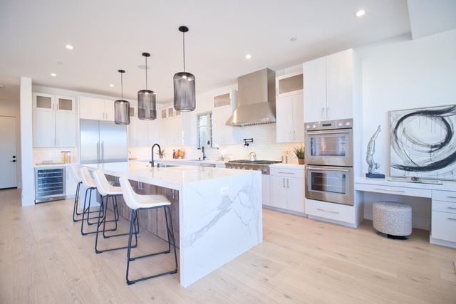 a large kitchen with stainless steel appliances a stove a sink dishwasher and a dining table with wooden floor