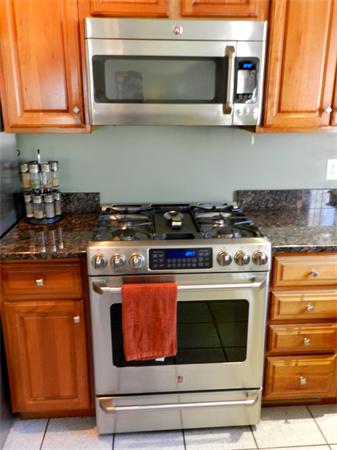 58 Pershing Road Boston, MA 02130 - Photo 11 of 30 a kitchen with stainless steel appliances granite countertop a stove and a microwave
