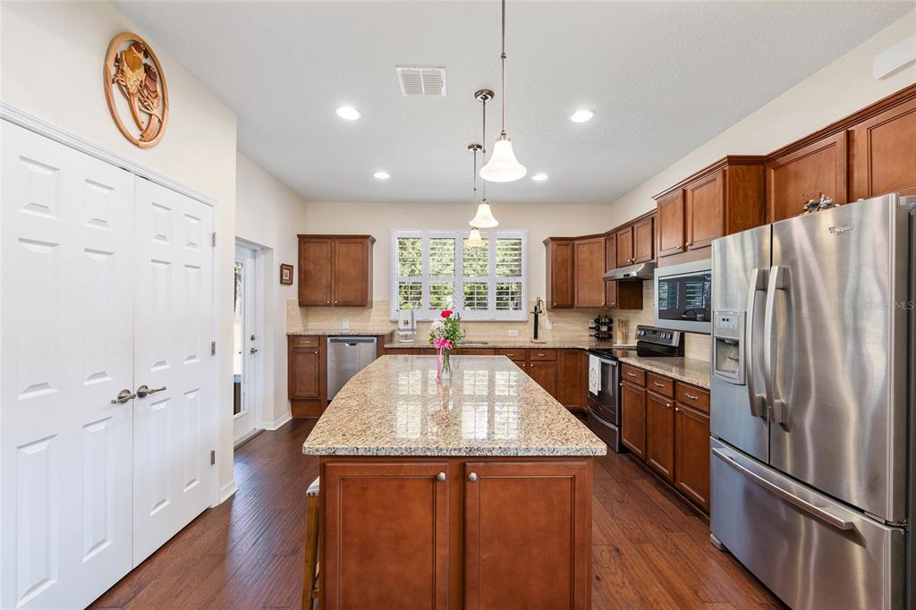 7676 Southwest 94th Circle Ocala, FL 34481 - Photo 12 of 45 a large kitchen with stainless steel appliances granite countertop a lot of counter space and wooden floor