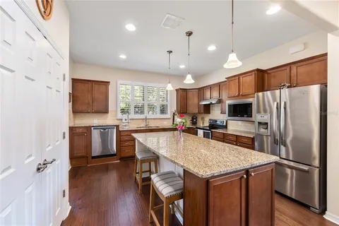 a kitchen with kitchen island a refrigerator a stove a sink and a island with wooden floor
