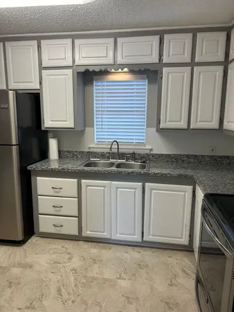 a kitchen with granite countertop a refrigerator sink and cabinets