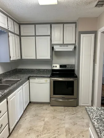 a kitchen with granite countertop a stove top oven microwave and cabinets