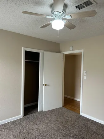 a view of an empty room with a chandelier fan