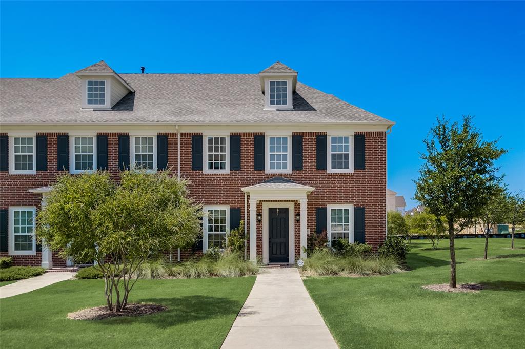 Colonial house featuring brick siding, roof with shingles, and a front lawn