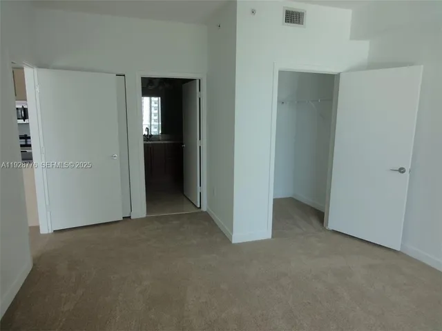 a view of an empty room with closet and wooden door