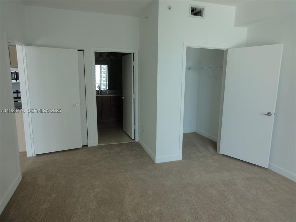 79 Southwest 12th Street, Unit 1203S Miami, FL 33130 - Photo 5 of 21 a view of an empty room with closet and wooden door