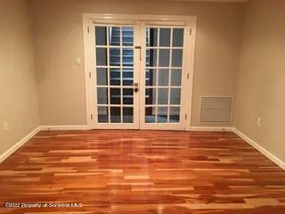 a view of an empty room with wooden floor and windows