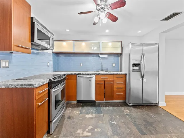 a kitchen with stainless steel appliances granite countertop a stove a sink and a refrigerator