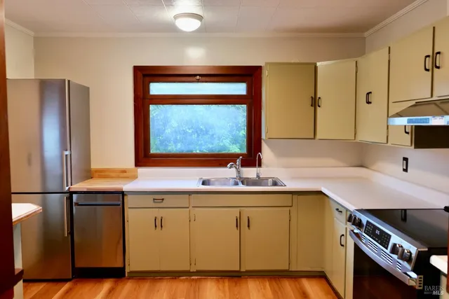 a kitchen with stainless steel appliances a sink a stove and white cabinets