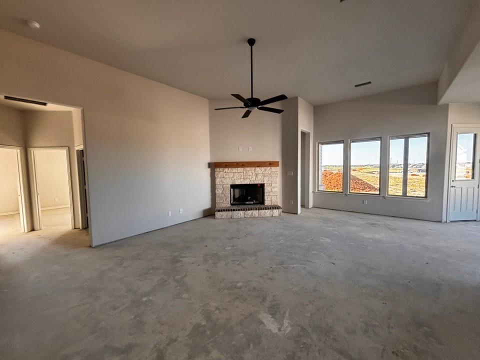 125 Pheasant Run Drive Rhome, TX 76078 - Photo 4 of 11 Spacious room featuring a stone-clad fireplace with a wood mantel, multiple large windows, and a ceiling fan