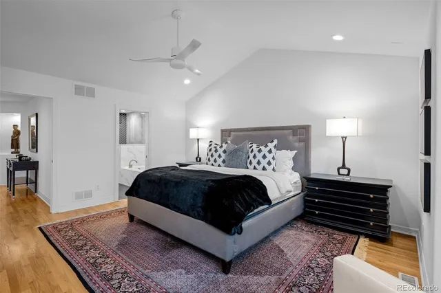 a spacious bedroom with a bed a rug and wooden floor