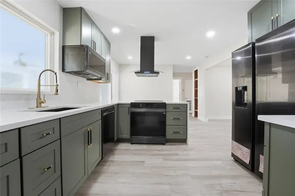 a kitchen with stainless steel appliances kitchen island granite countertop a refrigerator and a sink