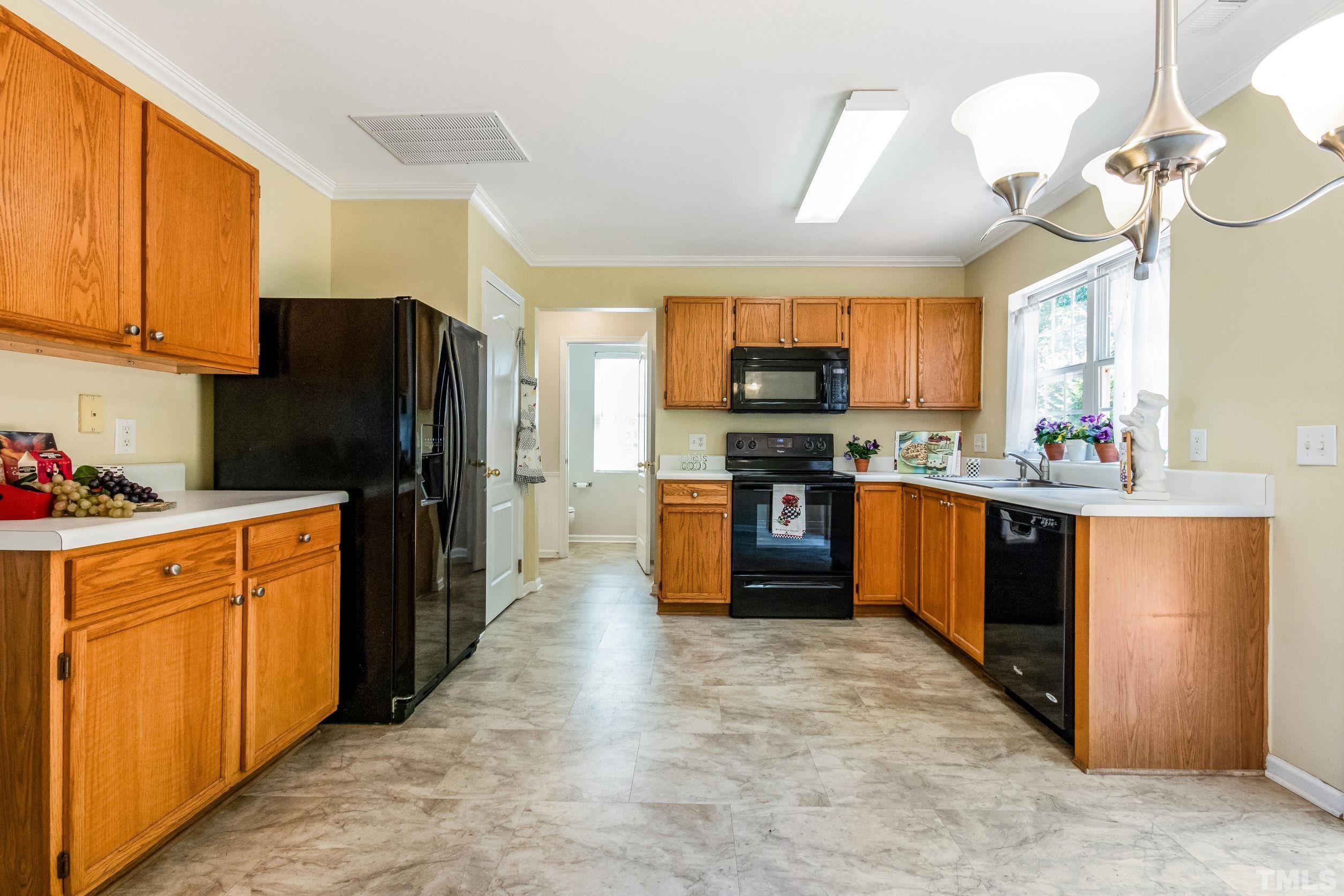 4827 Shallowbrook Trail Raleigh, NC 27616 - Photo 7 of 30 a kitchen with stainless steel appliances wooden cabinets a center island and a refrigerator