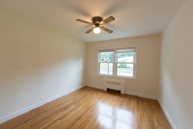 an empty room with wooden floor fan and windows