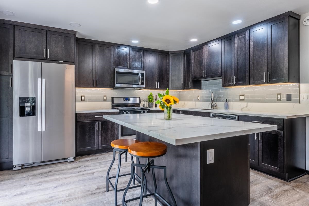 a kitchen with kitchen island granite countertop wooden cabinets a refrigerator and a sink