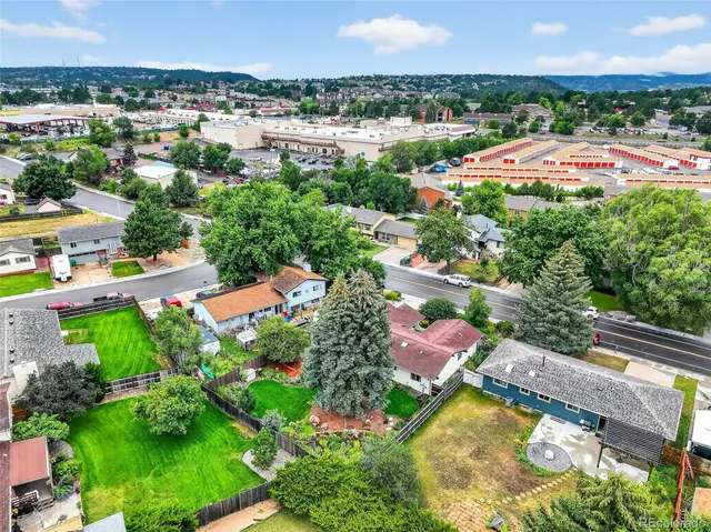 an aerial view of residential houses with outdoor space and trees all around