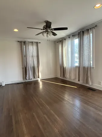 an empty room with wooden floor fan and windows