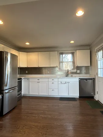 a large kitchen with granite countertop white cabinets and stainless steel appliances