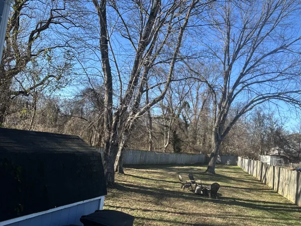 a view of backyard with wooden fence and large trees