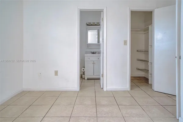 a view of an empty room with closet and a window