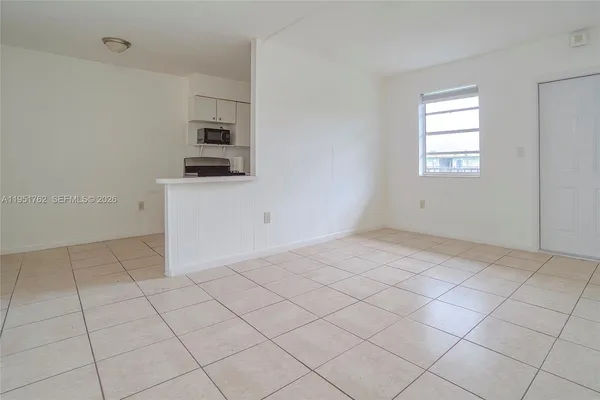 a view of kitchen and empty room with windows
