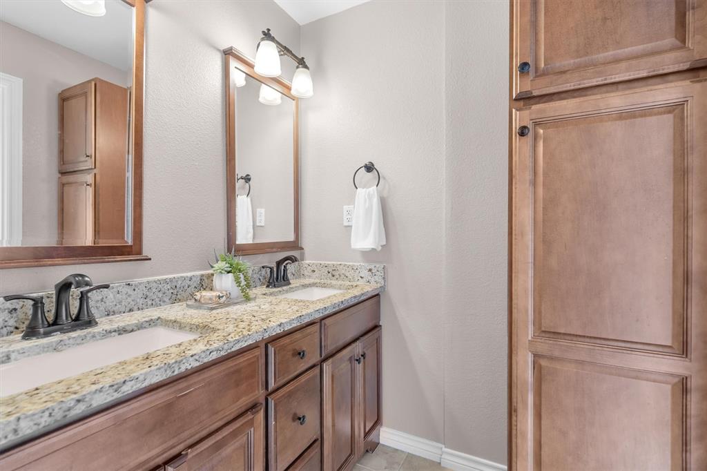 410 Simmons Road Double Oak, TX 75077 - Photo 28 of 40 Full bathroom with dual vanity and warm wood-toned cabinetry — stylish and functional.