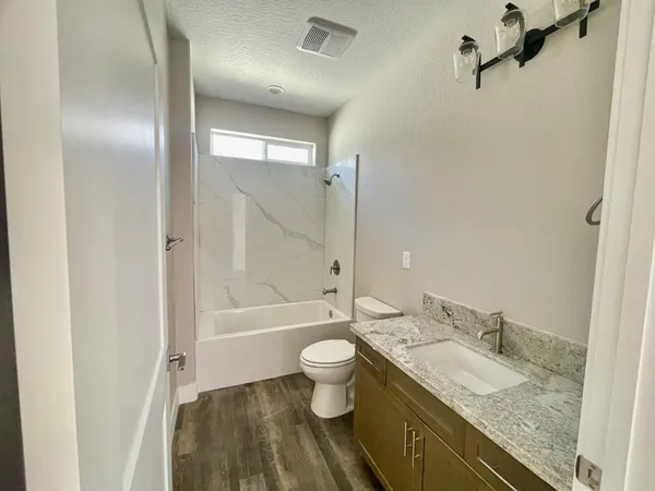 a bathroom with a granite countertop sink a toilet and shower