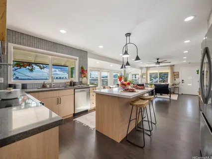 a kitchen with stainless steel appliances granite countertop a sink dishwasher a stove and a dining table with wooden floor