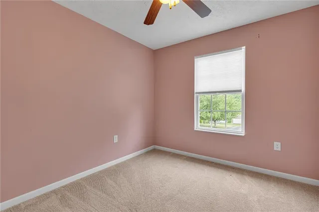 an empty room with chandelier fan and windows