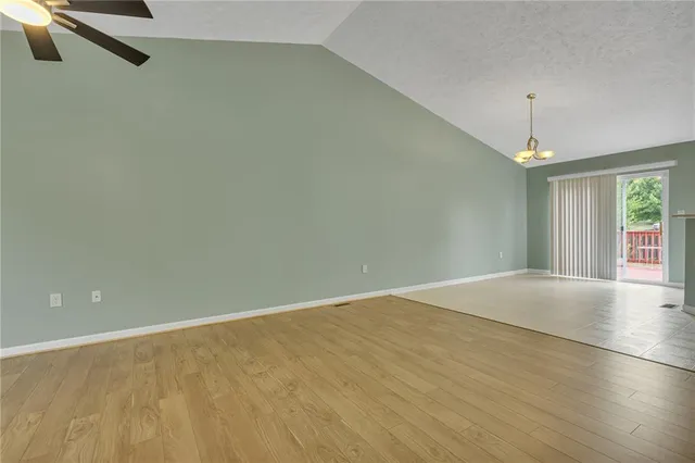 an empty room with a chandelier fan and windows