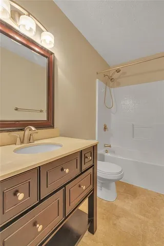 a bathroom with a granite countertop sink a toilet mirror and bathtub