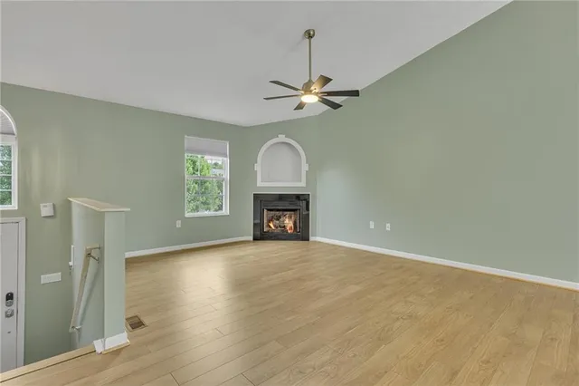 a view of a livingroom with a fireplace a ceiling fan and wooden floor