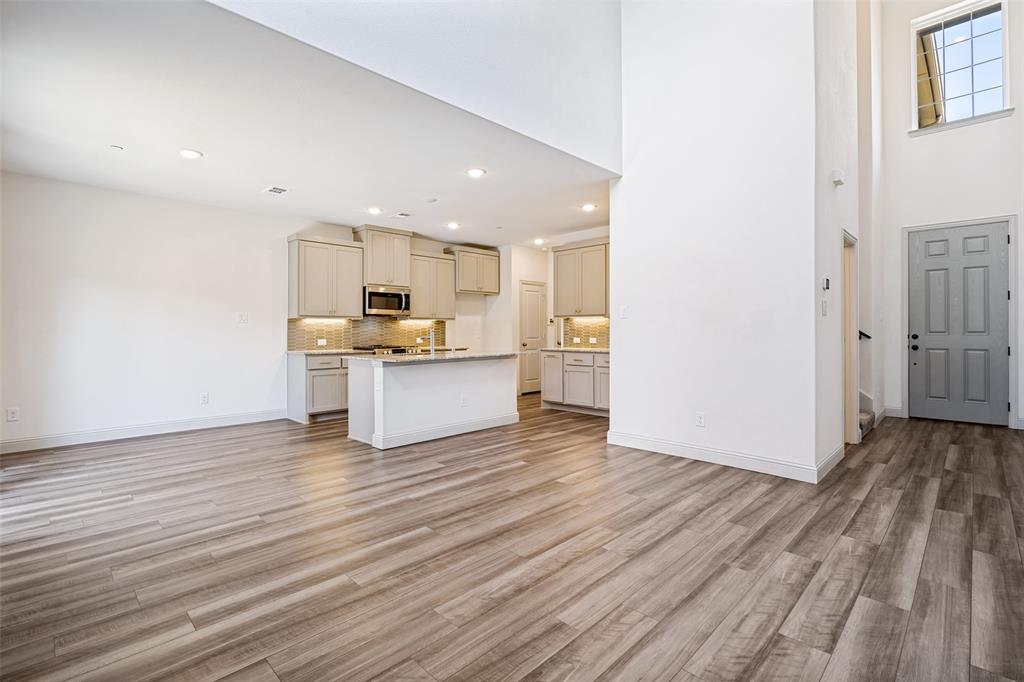 1006 Emil Place Allen, TX 75013 - Photo 7 of 28 Open-concept living space featuring wood-finish flooring, a contemporary kitchen, and soaring ceilings