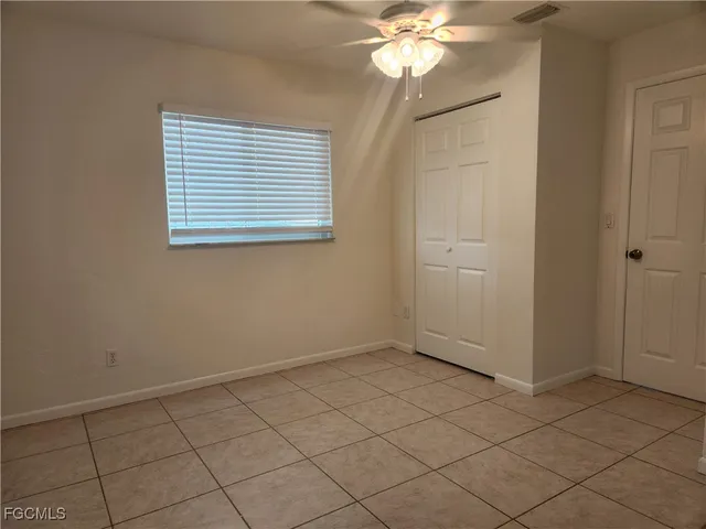 an empty room with windows and chandelier fan