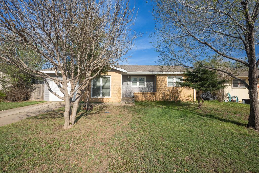 a view of a yard in front of a house with large trees