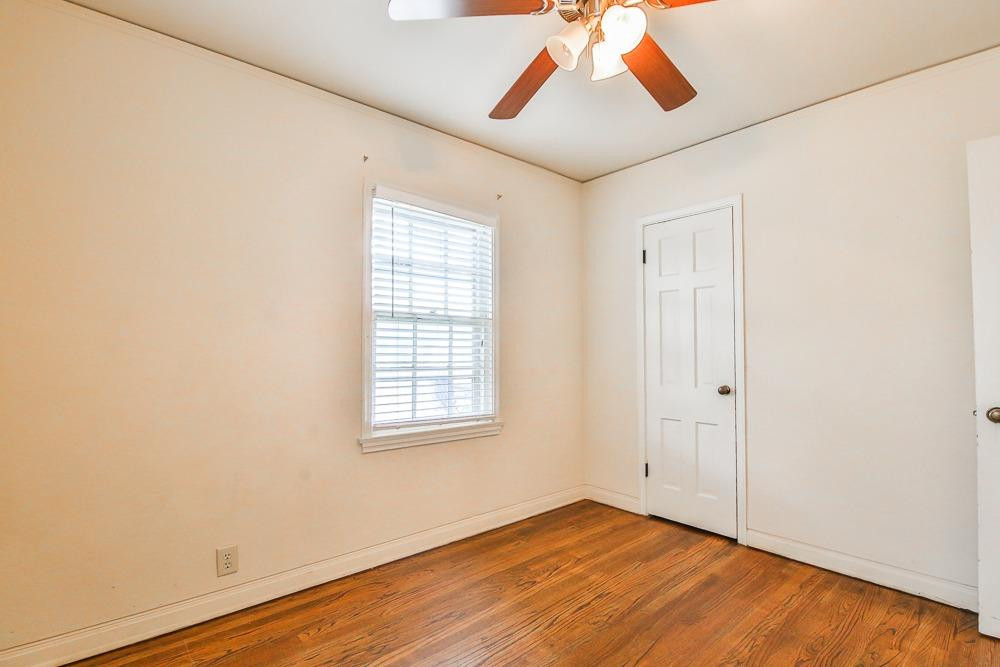 2318 29th Street Lubbock, TX 79411 - Photo 24 of 32 an empty room with wooden floor ceiling fan and windows