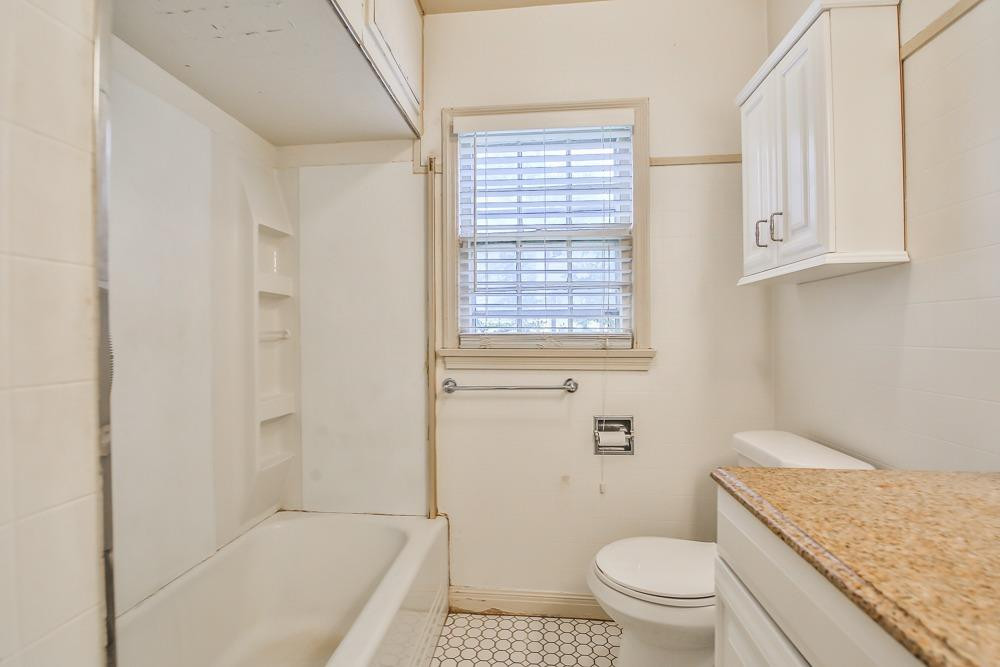 2318 29th Street Lubbock, TX 79411 - Photo 27 of 32 a bathroom with a granite countertop toilet a sink and a bathtub