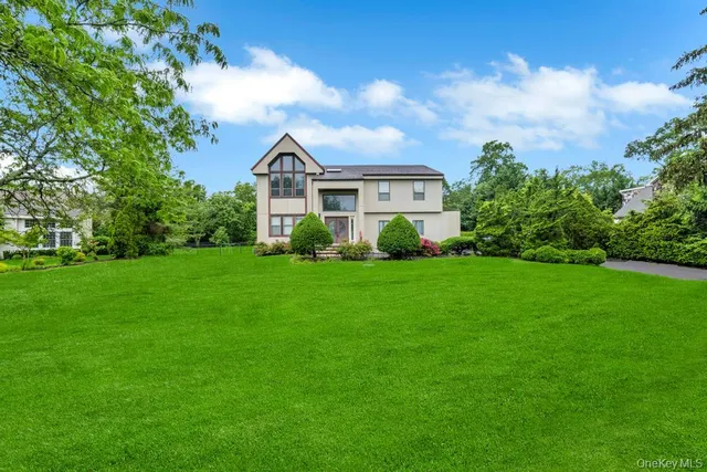 a view of a house with a big yard potted plants and large tree
