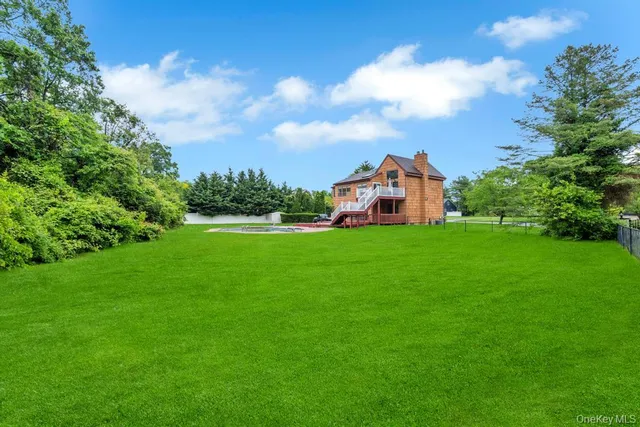a view of a house with a big yard and large trees