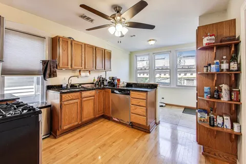 a kitchen with stainless steel appliances granite countertop a stove top oven a sink a dining table and chairs with wooden floor