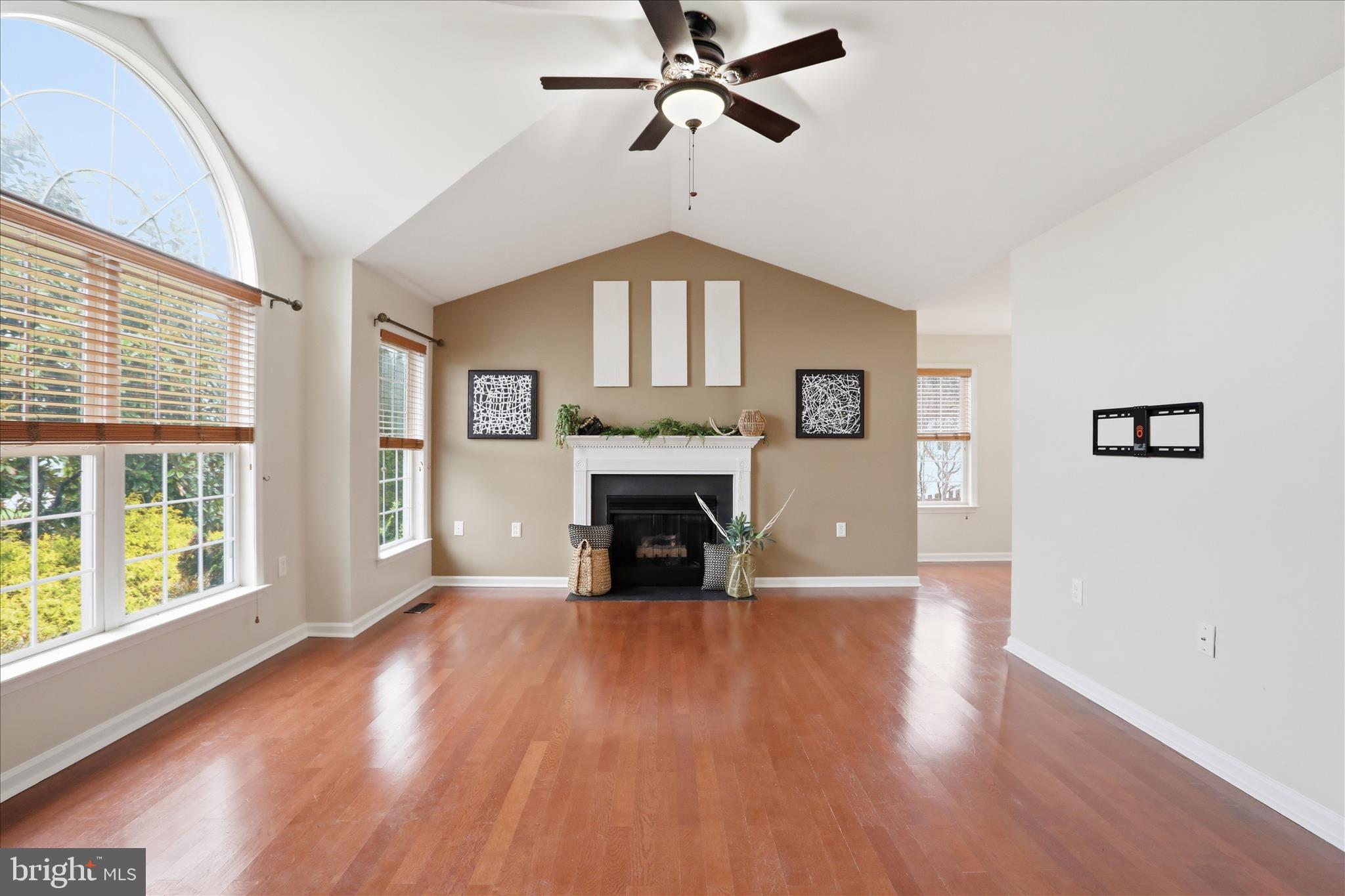 88 Grassy Meadow Road Charles Town, WV 25414 - Photo 4 of 44 an empty room with windows a fireplace a ceiling fan and wooden floor